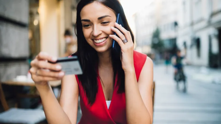 mujer hablando por celular y mirando tarjeta