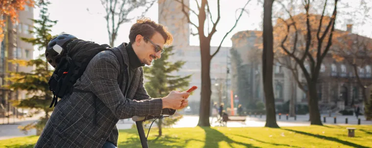 hombre en monopatín con el celular en la mano.